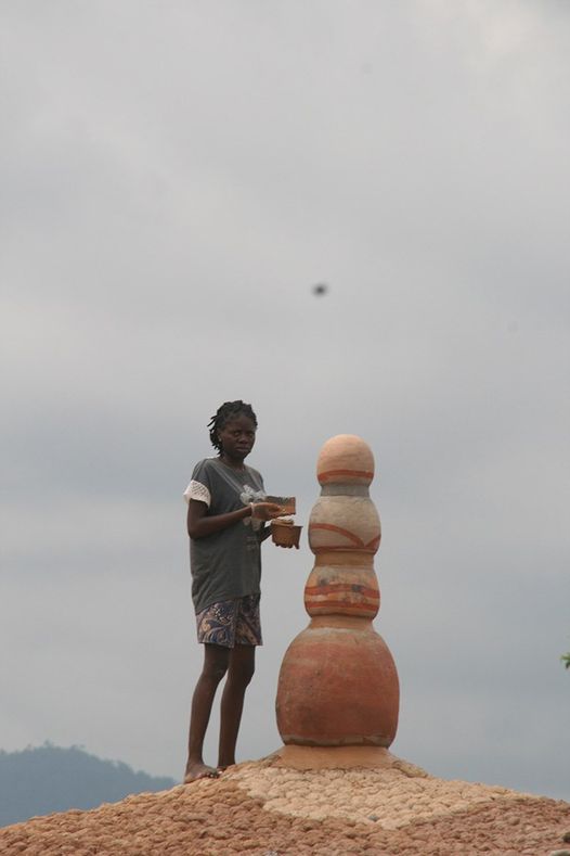 a picture of the Artist and curator of Akodi Orisa adding finishing touches to the phallic-nipple crown of the dome.