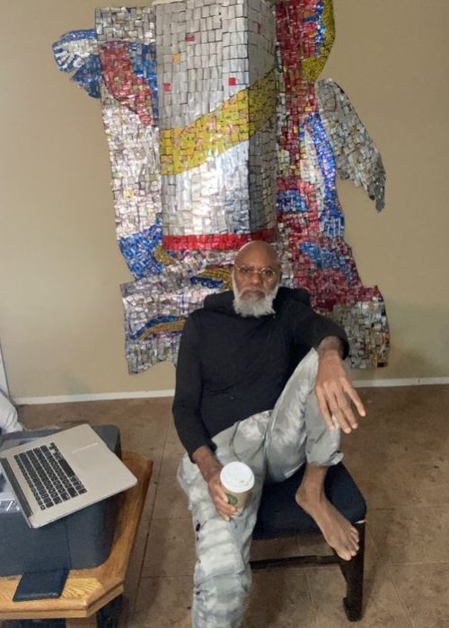 A picture of Moyo Okediji sitting in front of his artwork